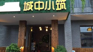 A restaurant entrance with a green awning and a sign in yellow characters.