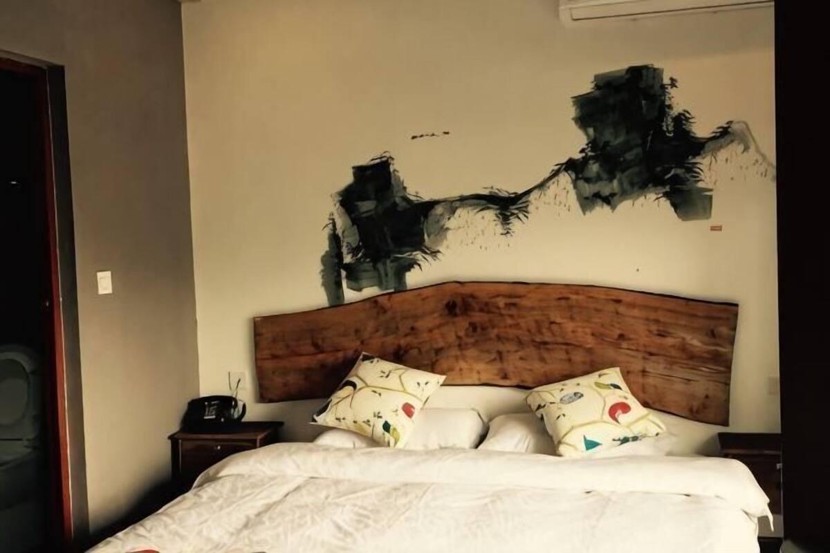 Ein Schlafzimmer mit hölzernem Kopfteil, einem Bett mit weißer Bettwäsche und einem Nachttisch mit Radio.