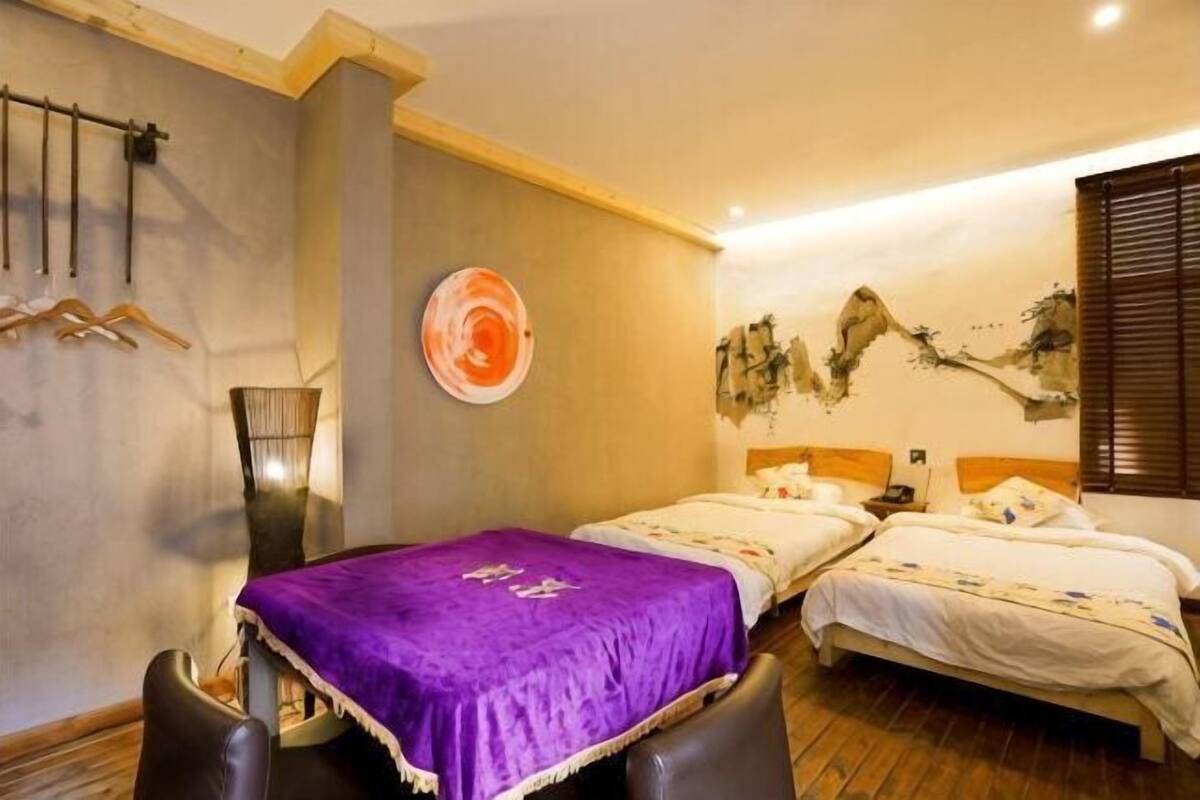 Ein Hotelzimmer mit zwei Betten, einem Esstisch und einer Wand mit einem Gemälde.