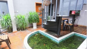 A small indoor garden with a water feature, potted plants, and a wooden table and chairs.