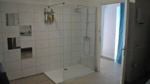 A bathroom with a shower, tiled walls, and a door leading to another room. - Havre de Paix (Fontenoy-le-Château)