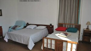 A bedroom with two single beds, a wooden headboard, a nightstand with a lamp, and a window with curtains. - Havre de Paix (Fontenoy-le-Château)