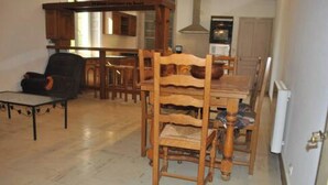 A dining area with wooden chairs and a table, a sofa, and a kitchen area in the background. - Havre de Paix (Fontenoy-le-Château)