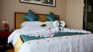 Una cama bien tendida con sábanas blancas, almohadas color turquesa y un arreglo floral.