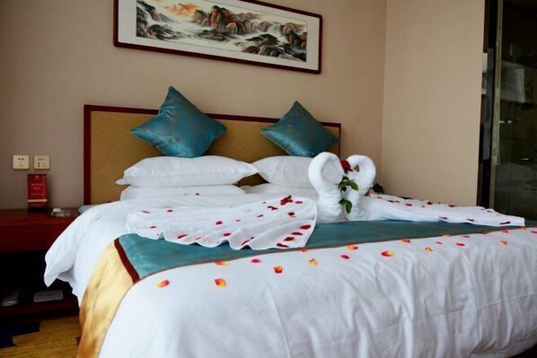 A neatly made bed with white linens, teal pillows, and a floral arrangement. - Wassim Hotel &Resorts (Neiqiu)