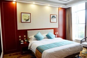 A hotel room with a large bed, two pillows, a nightstand, a desk, and a window with curtains. - Wassim Hotel &Resorts (Neiqiu)