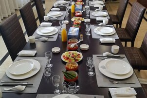 A dining table set with plates, glasses, and cutlery, surrounded by chairs.