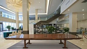 Un vestíbulo amplio con una gran mesa de madera, zonas de estar y una escalera.