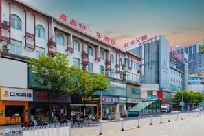 Una calle con una hilera de tiendas y un edificio con un cartel que dice 'Xinhua'.