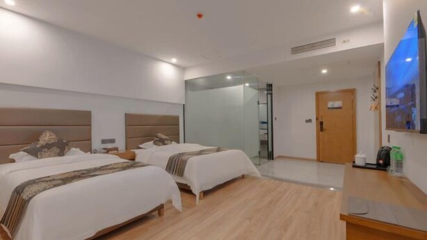 A modern hotel room with two beds, a glass partition, a wooden floor, a reception desk, and a flat-screen TV. - Fulante Le Hotel (Zhangjiajie Pedestrian Street) (Zhangjiajie)