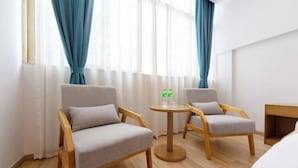 A hotel room with two wooden chairs, a small round table with a bottle and a glass, and a bed in the background. - Fulante Le Hotel (Zhangjiajie Pedestrian Street) (Zhangjiajie)