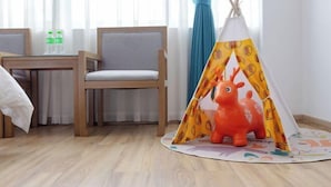 A room with a wooden chair, a small table with water bottles, and a colorful play tent with a toy animal. - Fulante Le Hotel (Zhangjiajie Pedestrian Street) (Zhangjiajie)
