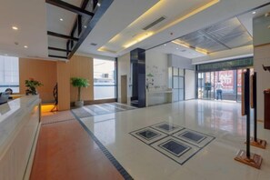 A spacious lobby with a reception desk, a potted plant, and a clear view of the entrance.