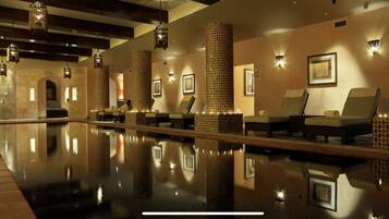 Uma área de spa com piscina refletora, espreguiçadeiras e painéis decorativos.