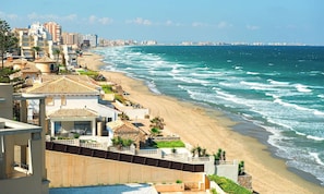 Um hotel à beira-mar com vista para a praia, uma piscina e vista para o horizonte urbano.