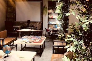 Une salle d’étude agréable, dotée d’une grande table, de bibliothèques et d’un écran de projection.