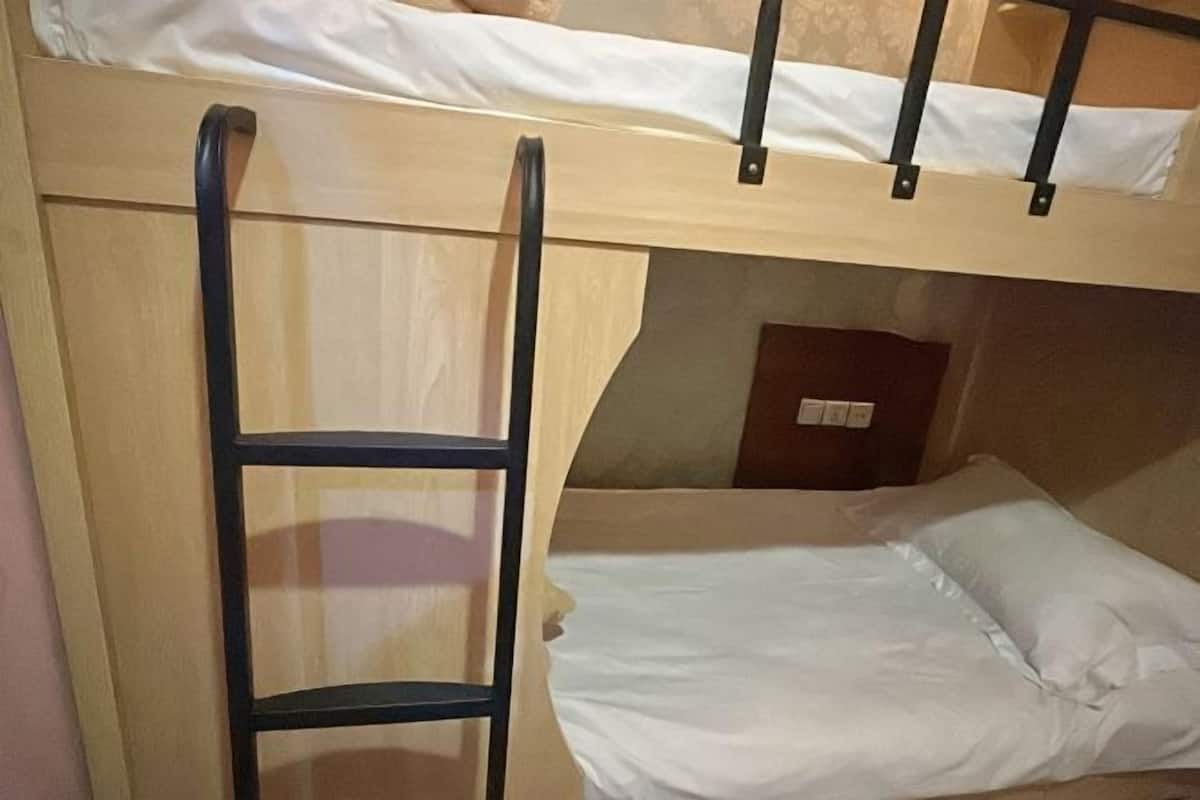 Uma cama beliche com escada, colchão branco e cabeceira de madeira.