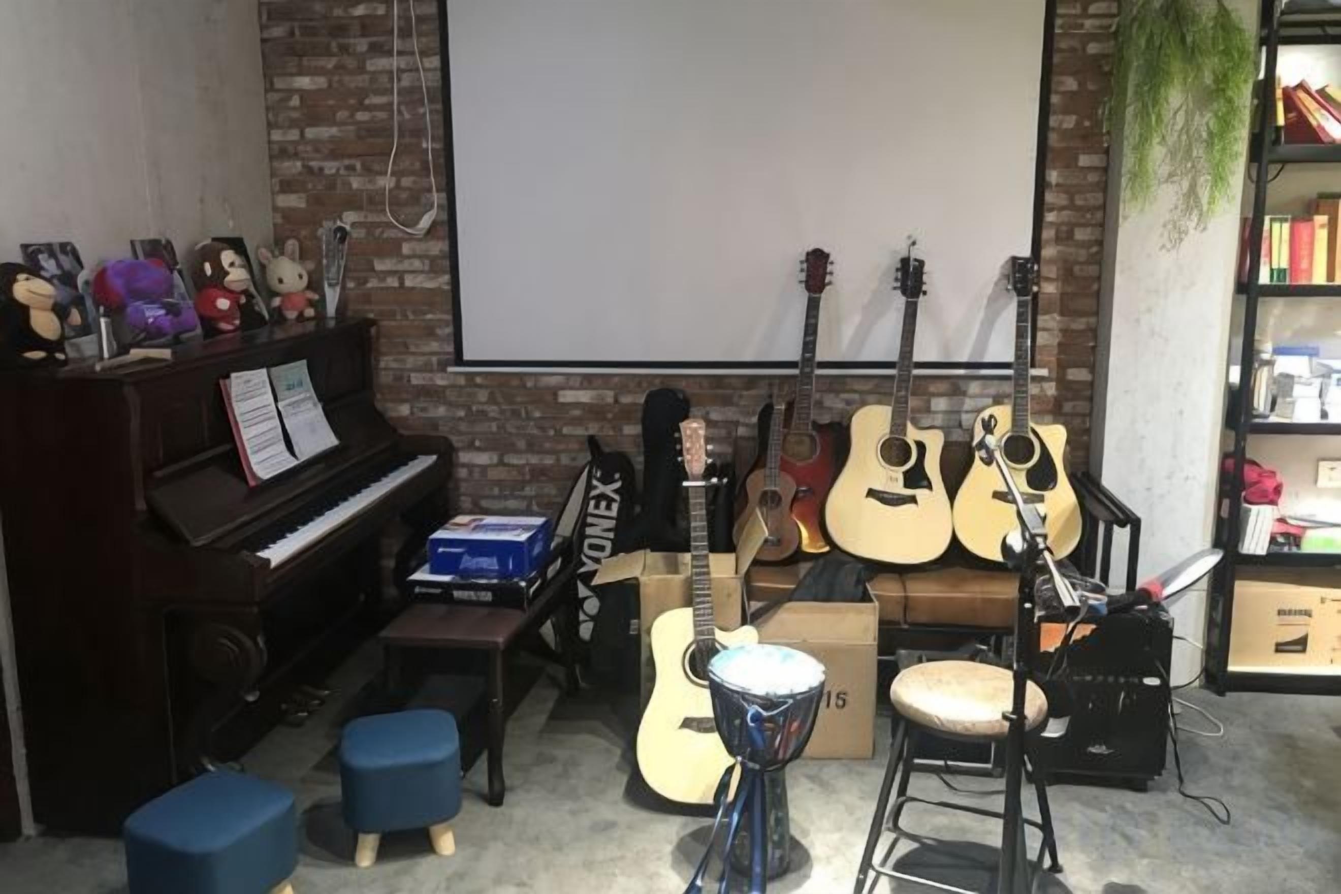Sala de música com um piano, guitarras e uma tela de projeção.