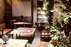 A cozy room with a large table, chairs, a globe, and a bookshelf. - Not Alone Minyao Youth Hostel (Shenyang)