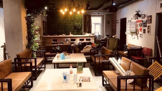 A restaurant with a central table, booths, and a bar area. - Not Alone Minyao Youth Hostel (Shenyang)