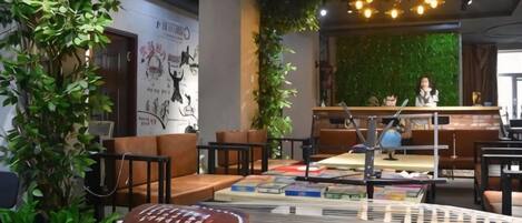 A modern lounge area with seating, a reception desk, and a green wall.