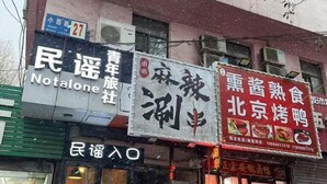 A building with multiple signs, including one for 'Notalone' and another for '北京烤鸭' (Beijing Roast Duck). - Not Alone Minyao Youth Hostel (Shenyang)