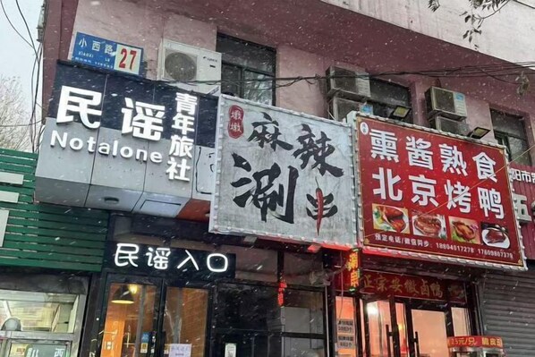 Um edifício com várias placas, incluindo uma para 'Notalone' e outra para '北京烤鸭' (Pato Assado de Pequim).