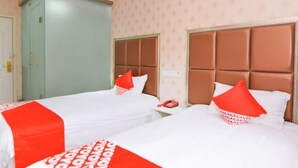 Een hotelkamer met twee bedden, elk met hoofdbord en rode kussens.