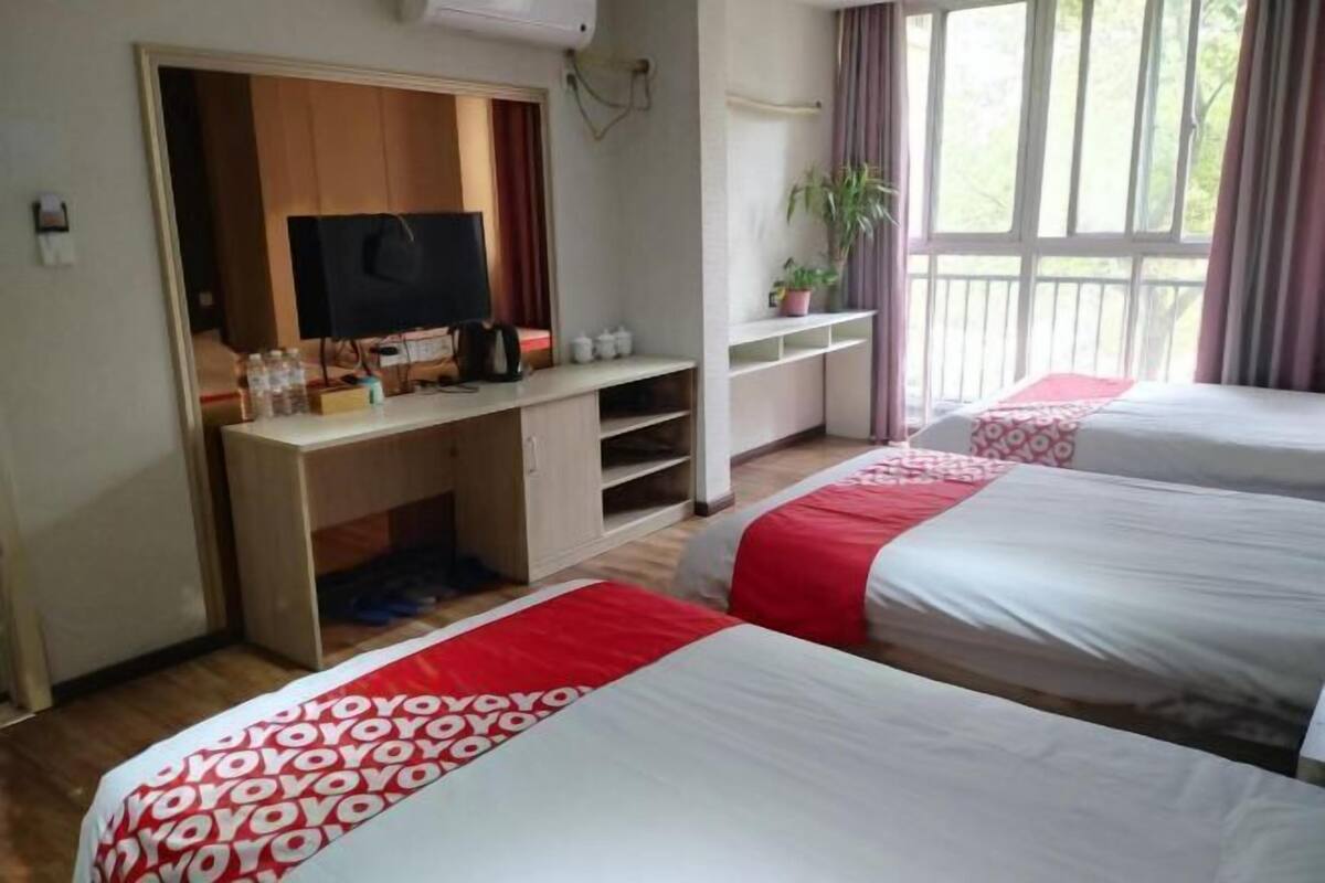 Habitación de hotel con dos camas, televisor, escritorio y ventana con cortinas.