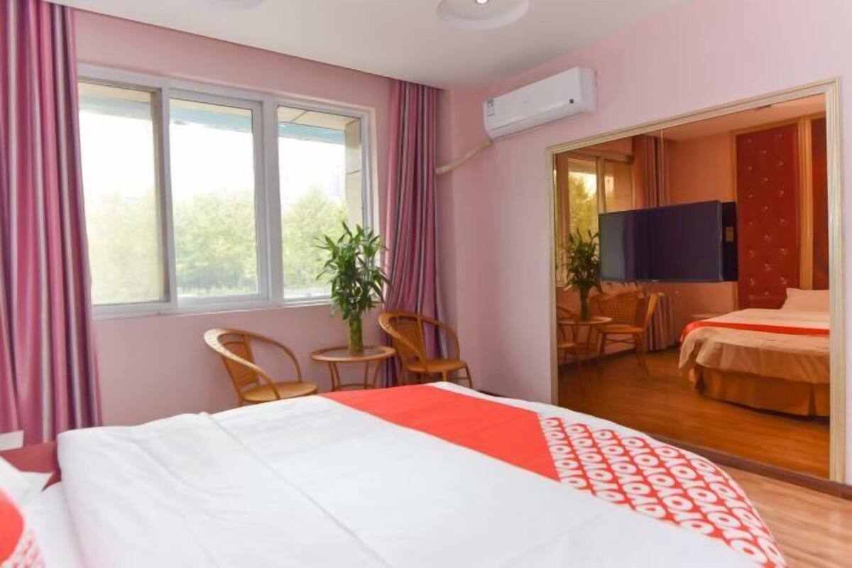 Una habitación de hotel con cama, televisor, una mesita con sillas y una planta.