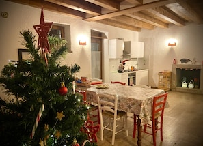 A dining area with a Christmas tree, wooden chairs, a table with a patterned tablecloth, and a fireplace with decorations. - Appartamento con piscina 10 posti letto (Ca' Isidora)