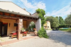 A rustic outdoor seating area with wooden benches and a large terracotta pot. - Appartamento con piscina 10 posti letto (Ca' Isidora)