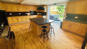 Una cocina moderna con armarios de madera, una isla central con taburetes, una estufa a gas y vistas a un patio trasero con un jacuzzi.