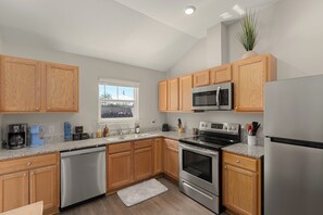 A modern kitchen with wooden cabinets, stainless steel appliances, and a window. - Ocean Oasis by Avantstay | Block to Beach | West PCB, Pet-Friendly (Panama City Beach)