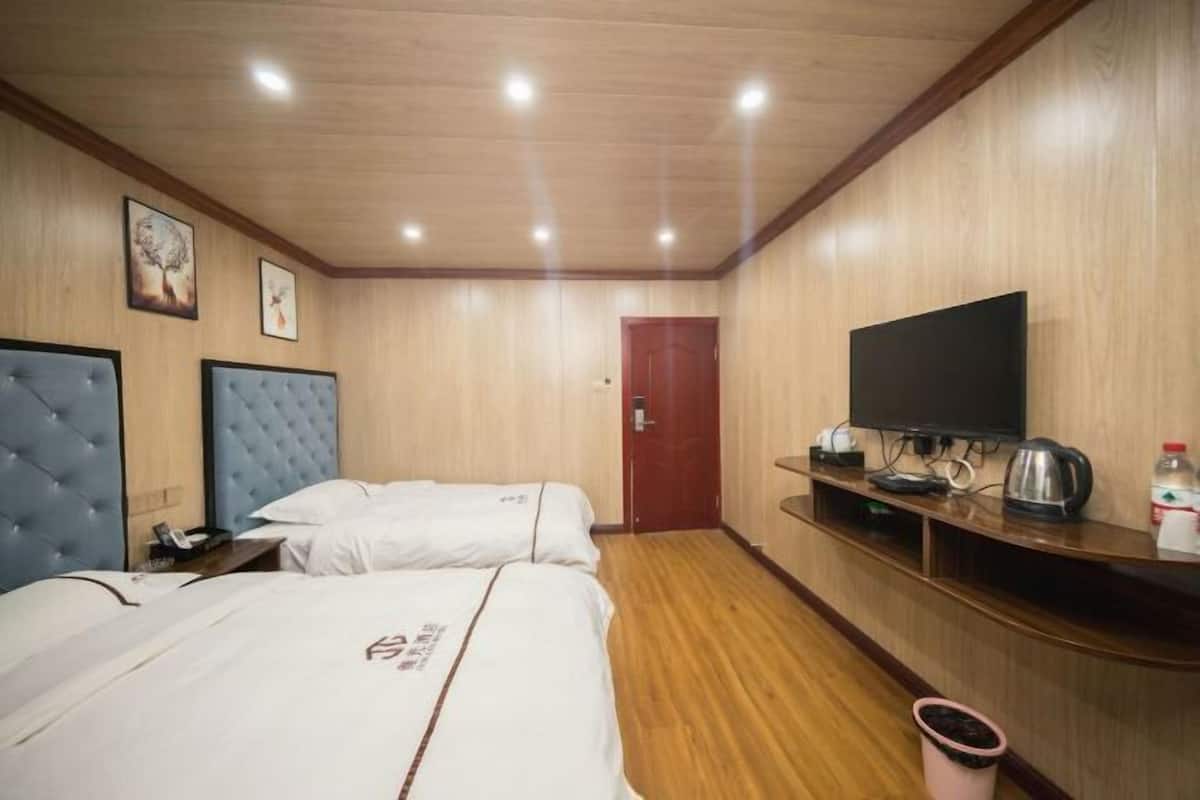 Une chambre d’hôtel avec deux lits, une télévision, un mur en bois et une porte.