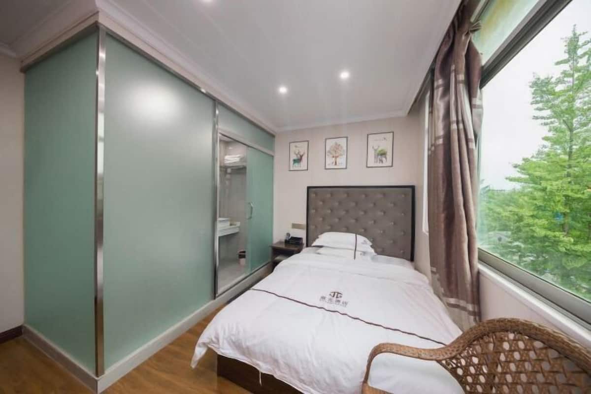 Une chambre à coucher avec un lit, une chaise, une armoire et une fenêtre donnant sur un beau paysage.