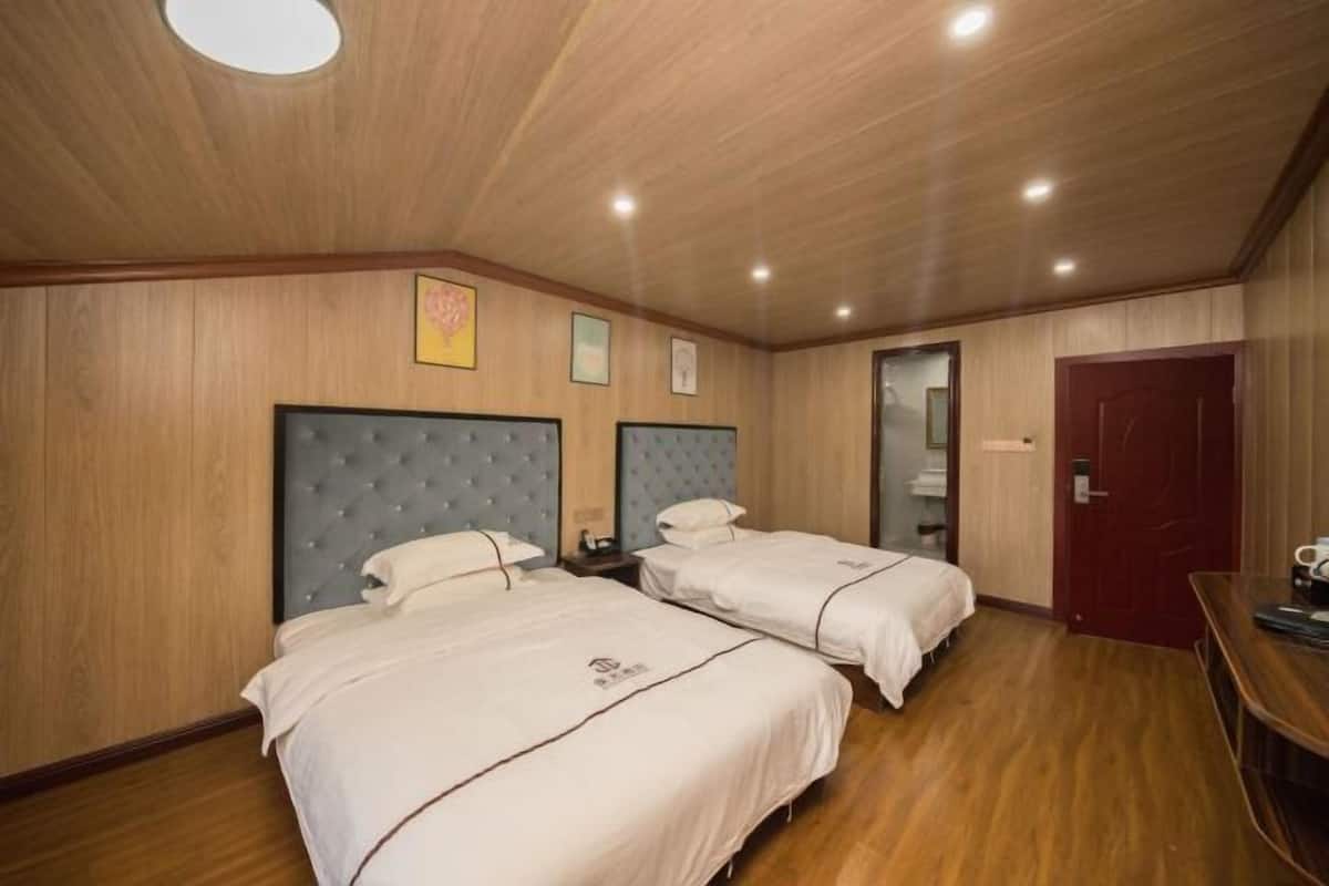 Une chambre d’hôtel avec deux lits, un plancher en bois, une porte rouge et une petite table avec une tasse.