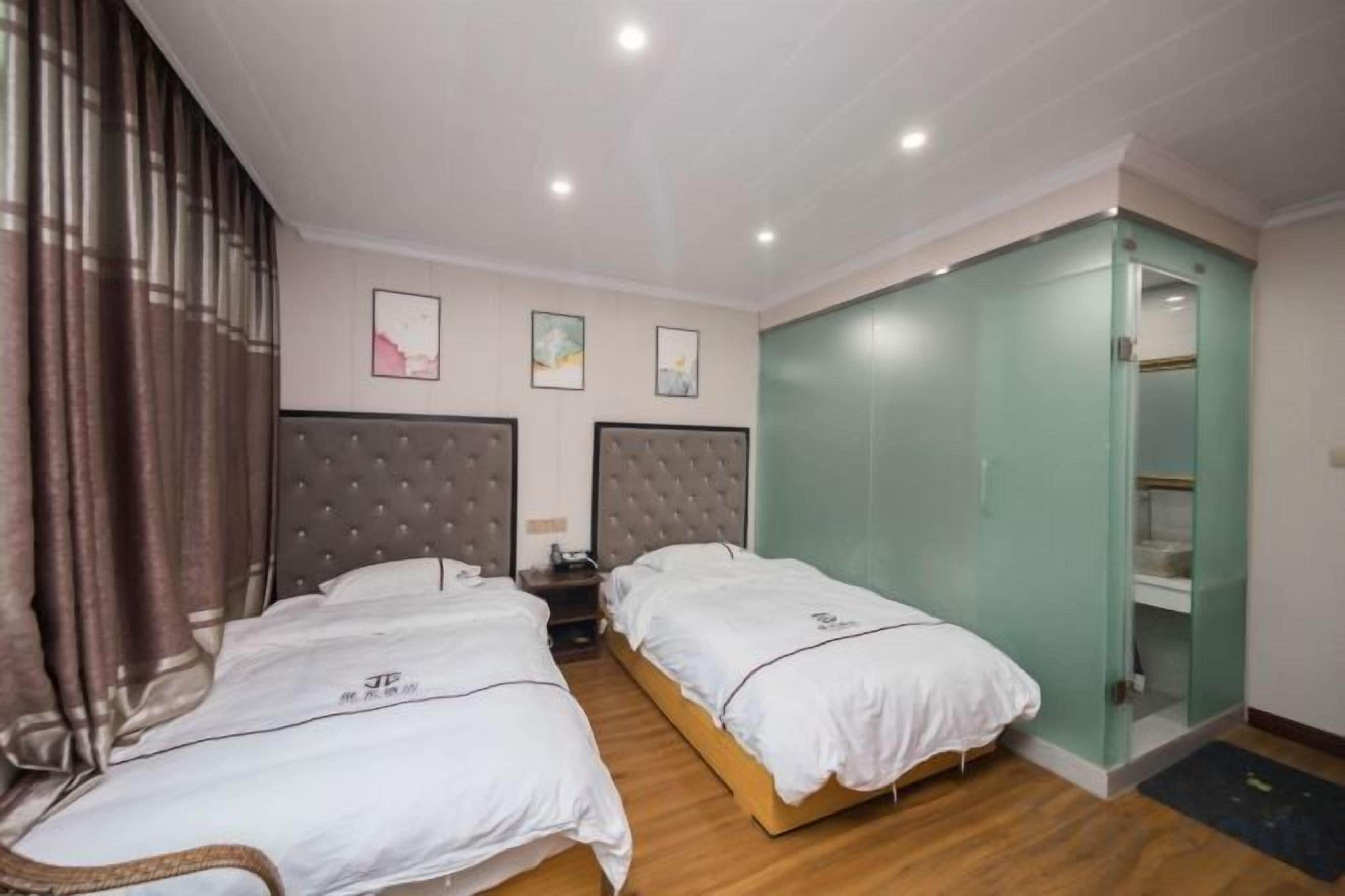 A hotel room with two beds, a wardrobe, and a small bedside table.