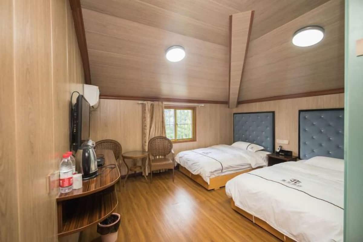 Une chambre avec deux lits, un bureau avec une chaise, une fenêtre et un luminaire au plafond.