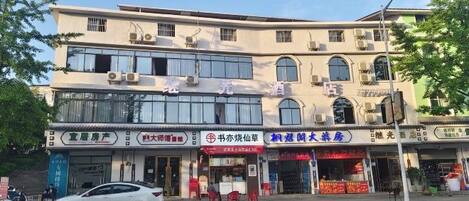 A multi-story building with various storefronts on the ground floor, including a restaurant and a convenience store.
