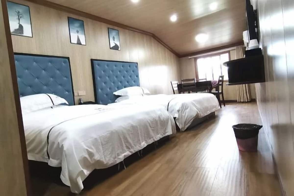 Une chambre d’hôtel avec deux lits, une table à manger et une poubelle.