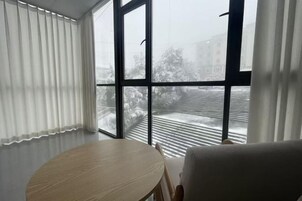 Um quarto com uma janela grande, uma mesa redonda e uma cadeira.