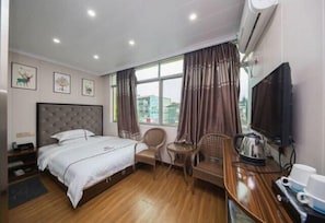 A hotel room with a bed, a small table with chairs, a television, and a window with curtains. - Jiguang Hotel (Chongqing)