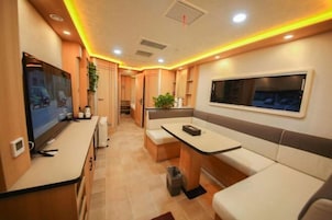 Una cocina compacta con estufa integrada, un área de comedor con banco, y un televisor montado en la pared.