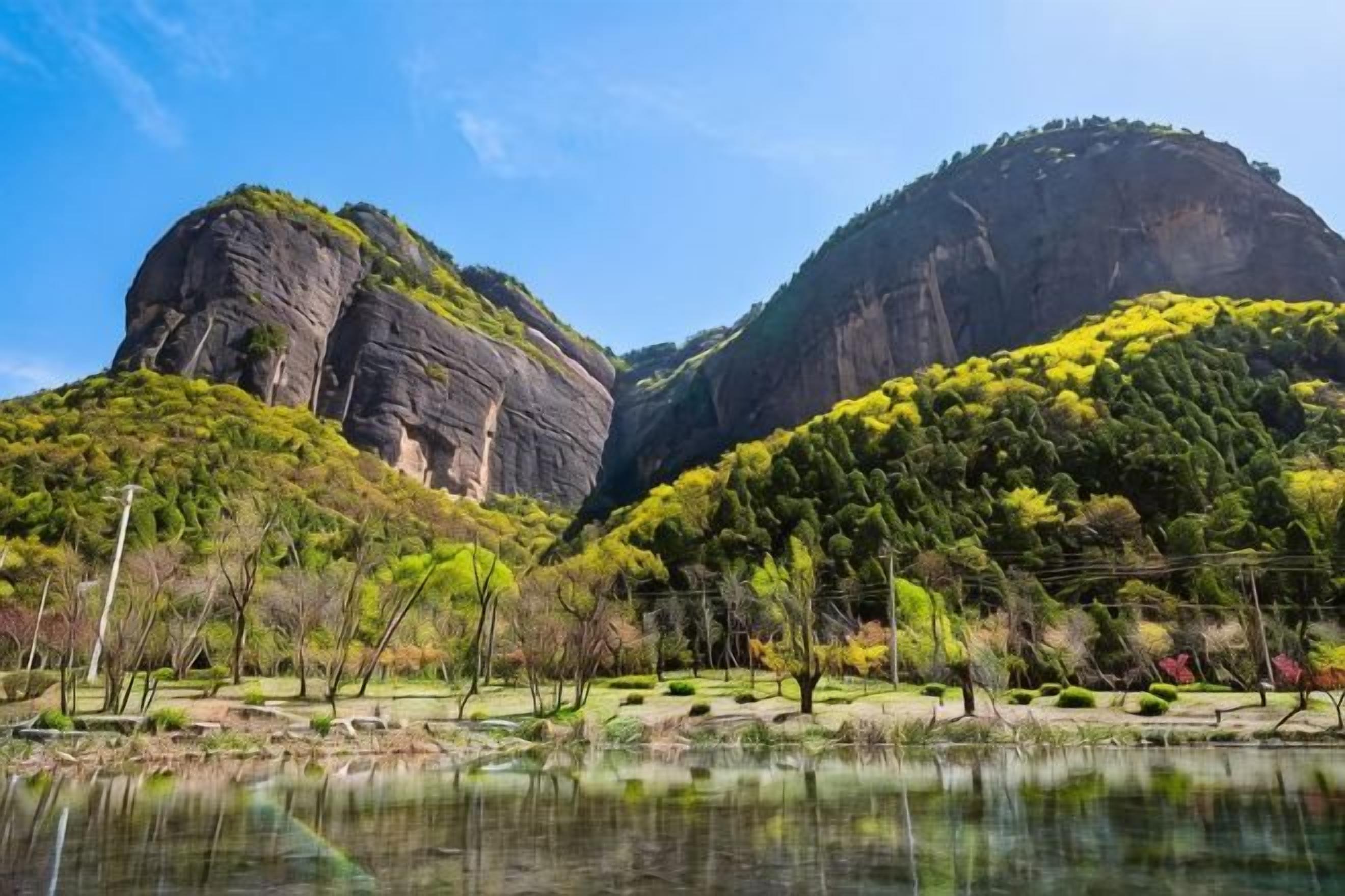 Un paysage montagneux avec un lac au premier plan et une grande formation rocheuse en arrière-plan.