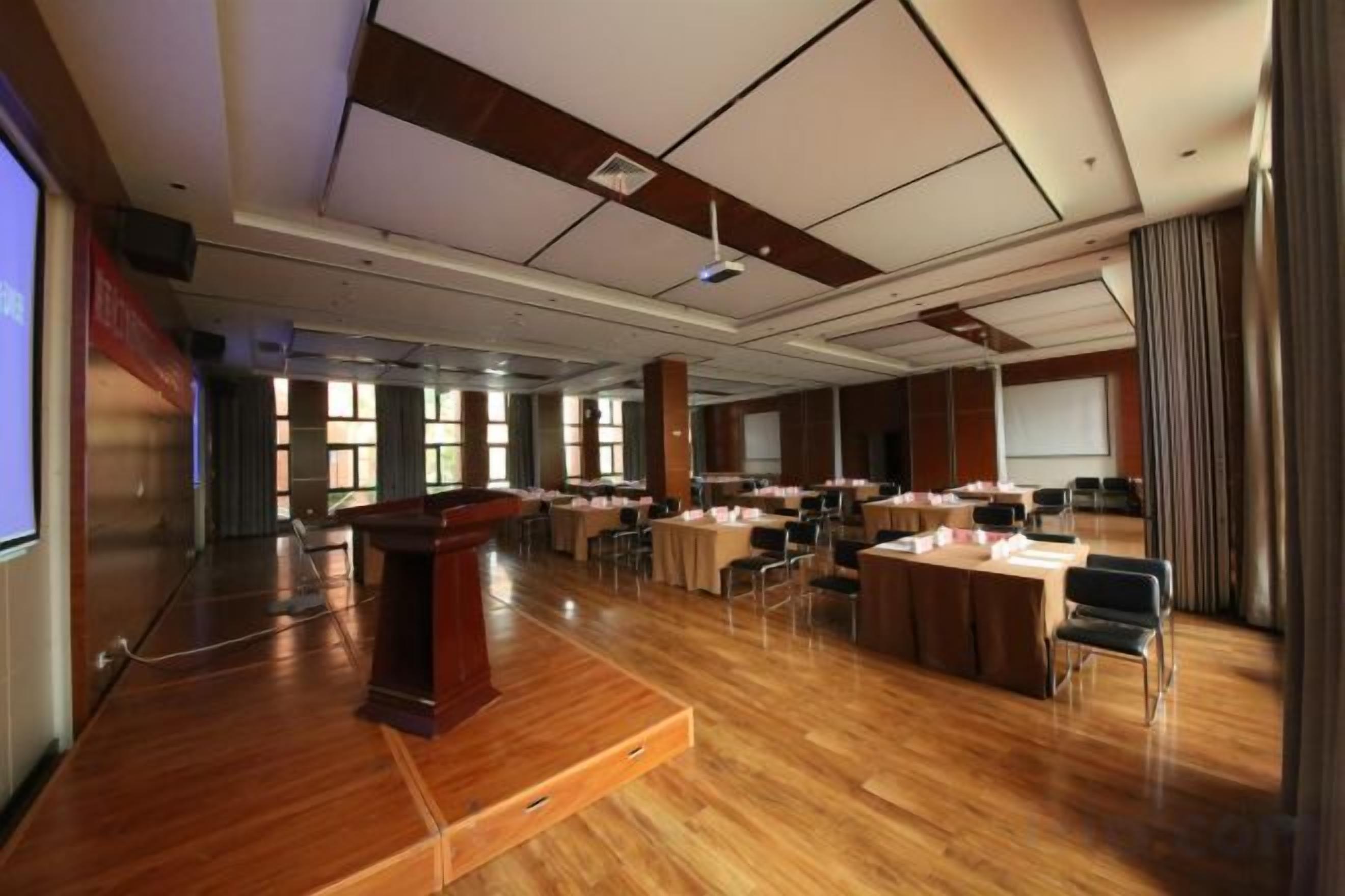 Ein Konferenzraum mit Holzboden, einem Rednerpult, Tischen und Stühlen, die für Besprechungen bereitstehen.