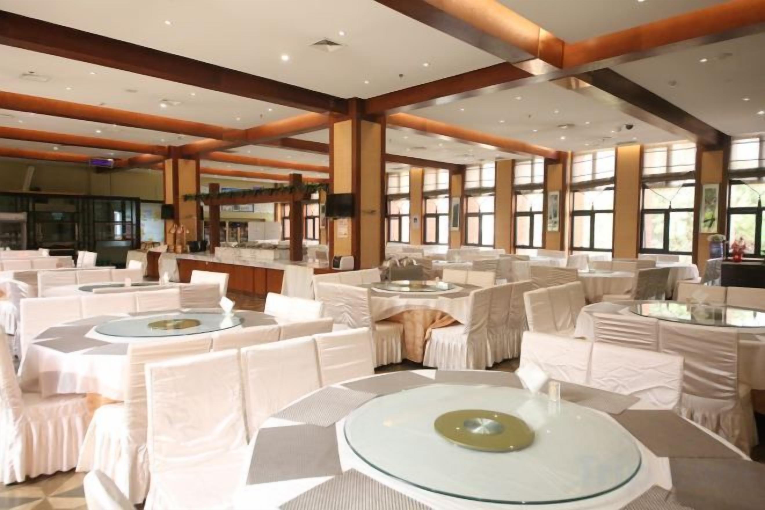 A banquet hall with round tables, white tablecloths, and chairs.