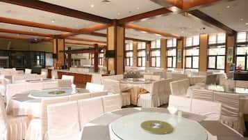 A banquet hall with round tables, white tablecloths, and chairs.