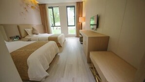 A hotel room with two beds, a desk, a TV, and large windows. - Zhaojin Shuyuan Hotel (Tongchuan)