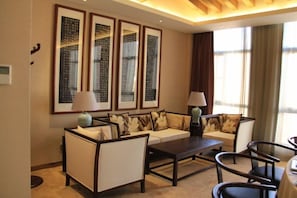 A modern living room with a sofa, armchairs, a coffee table, and framed artwork on the wall.